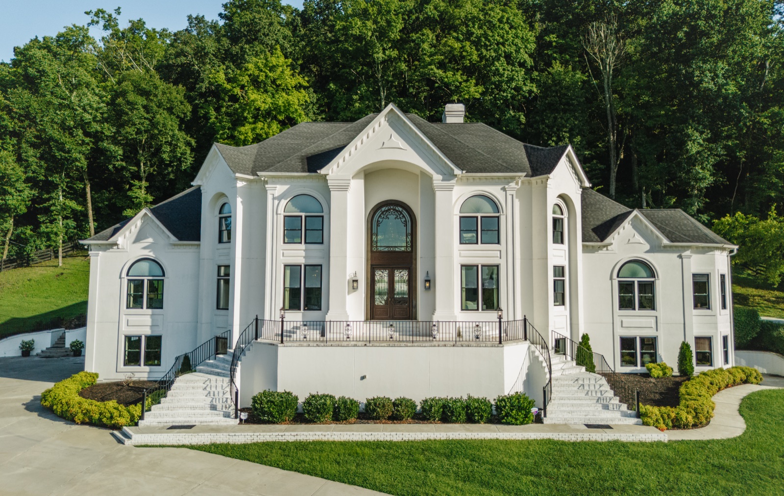 The mansion's front elevation: columned portico, twin curved staircases, and the iron front door.