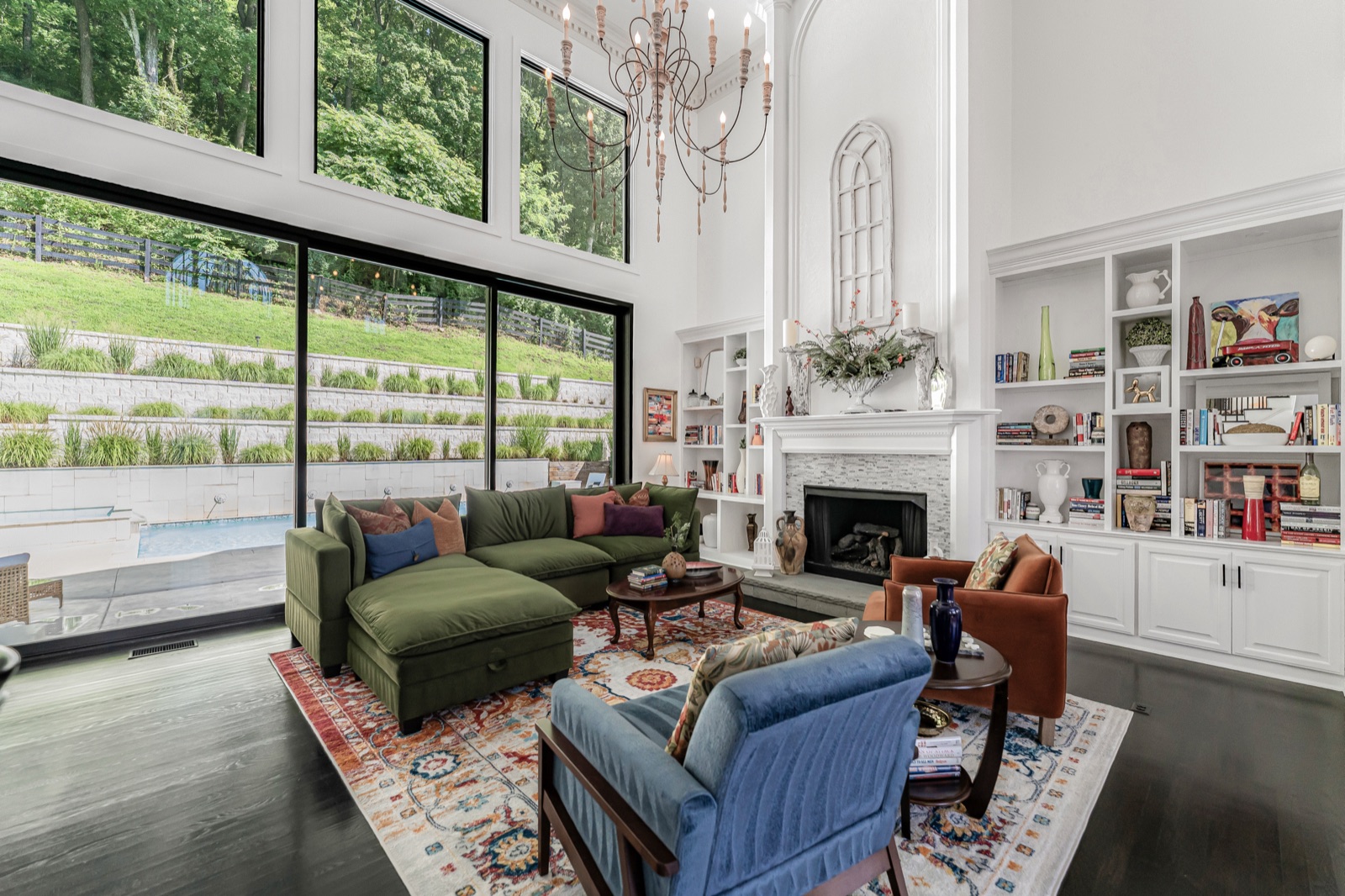 The great room opening through walls of glass to the pool terrace: 22-foot ceilings, stone fireplace.