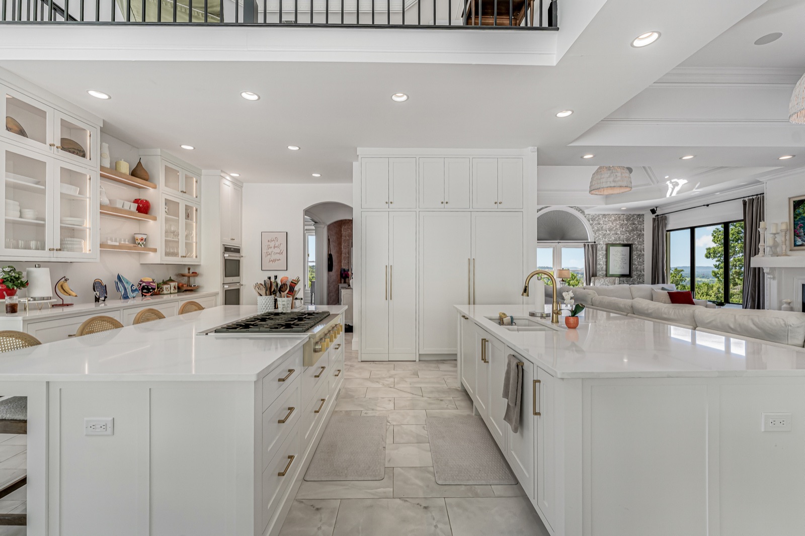 The kitchen wide: twin marble islands, the gas cooktop, and the great room and county beyond.