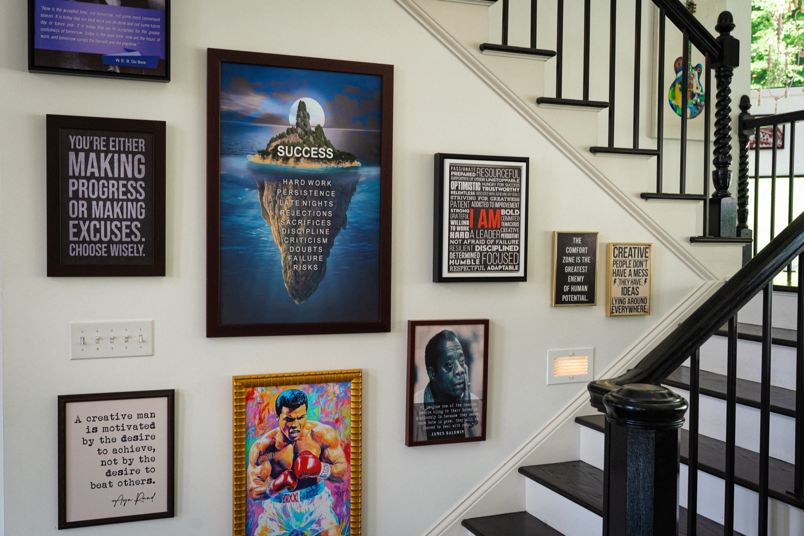 The stair wall hung corner to corner with framed statements on ambition, discipline, and achievement.