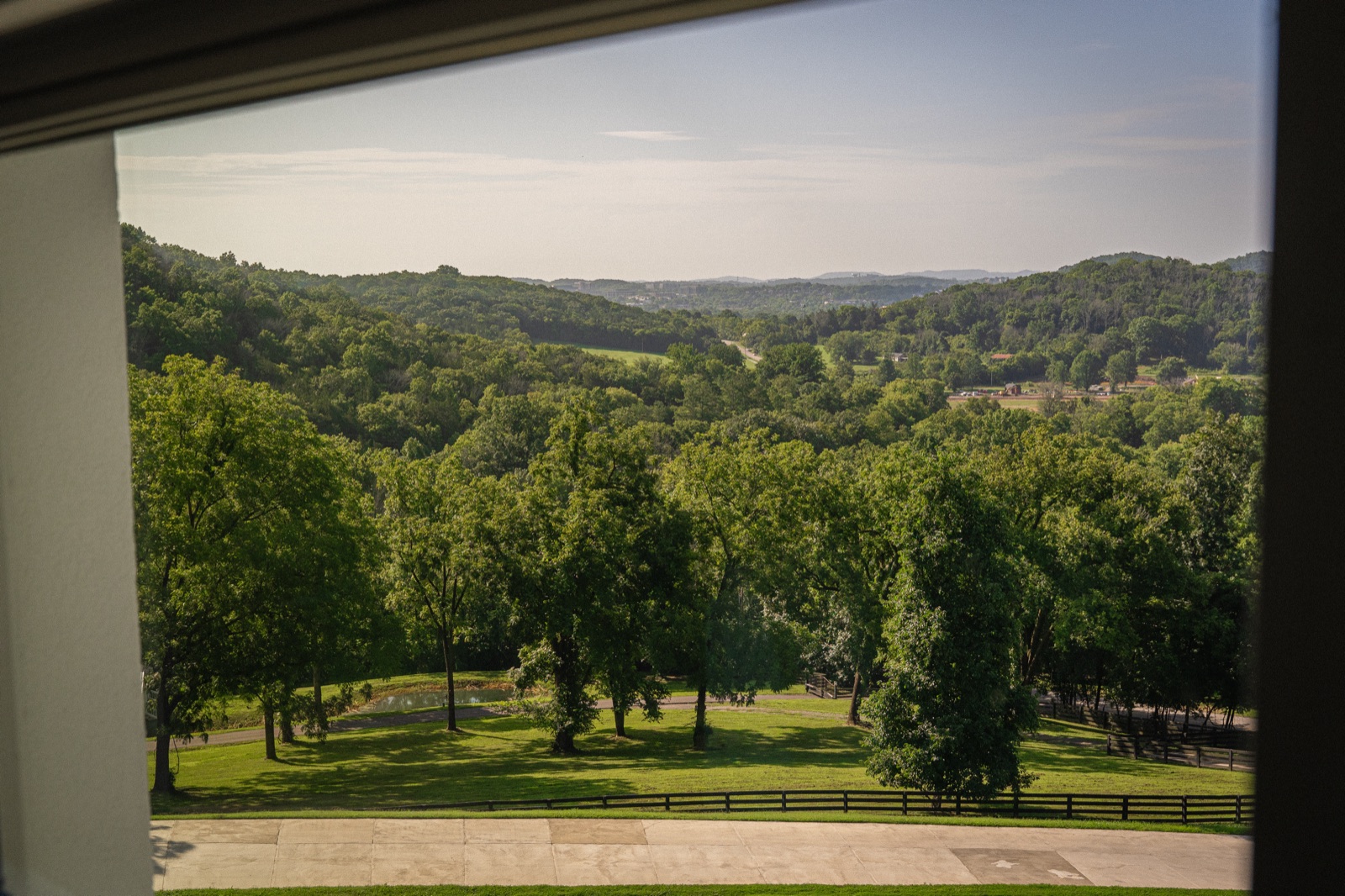 The county from an upstairs window: the lawn, the four-board fence, and the hills a family gets to know before it buys.